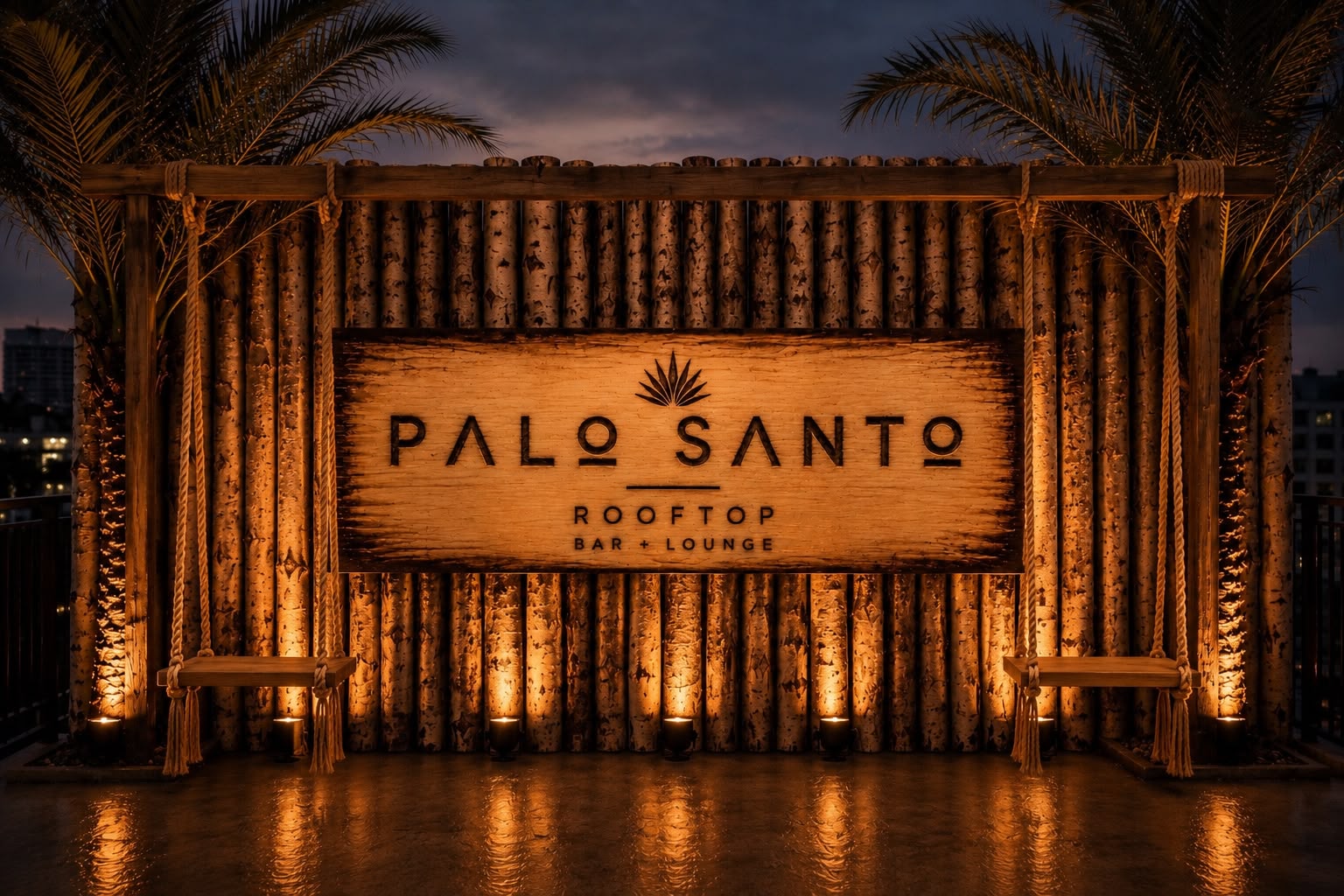 Illuminated Palo Santo Rooftop Bar + Lounge wooden sign with palms at dusk